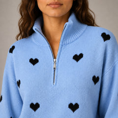 Close-up of the Amora sweater knit, silver half zipper and black heart pattern