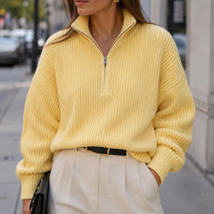 Woman styling the Vela Yellow half-zip sweater with tailored trousers outdoors